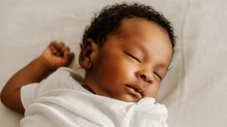 Baby sleeping on their back in white t-shirt