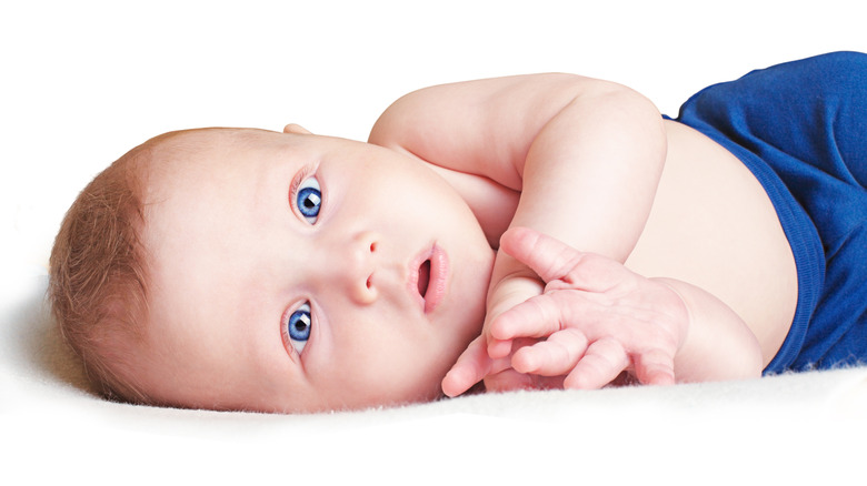 Baby with blue eyes lying on their side