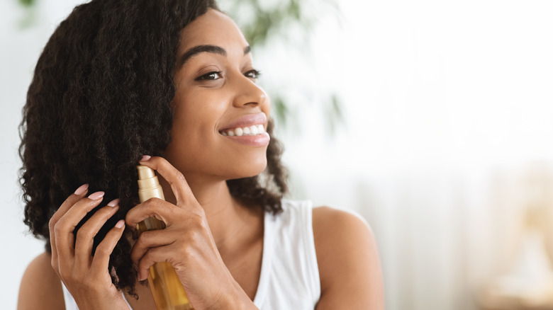 Woman spraying hair product in hair