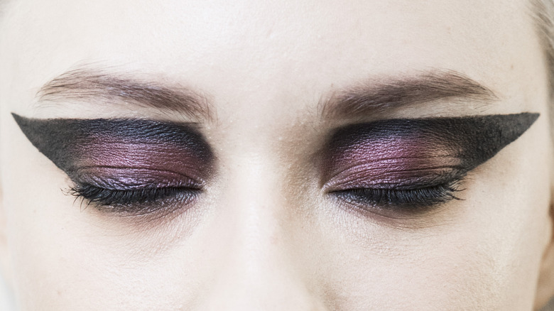 close-up of woman's eyes with dramatic duochrome eyeshadow and thick graphic black eyeliner