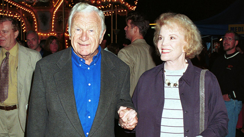 Eddie Albert and Nanette Fabray holding hands in front of a carousel