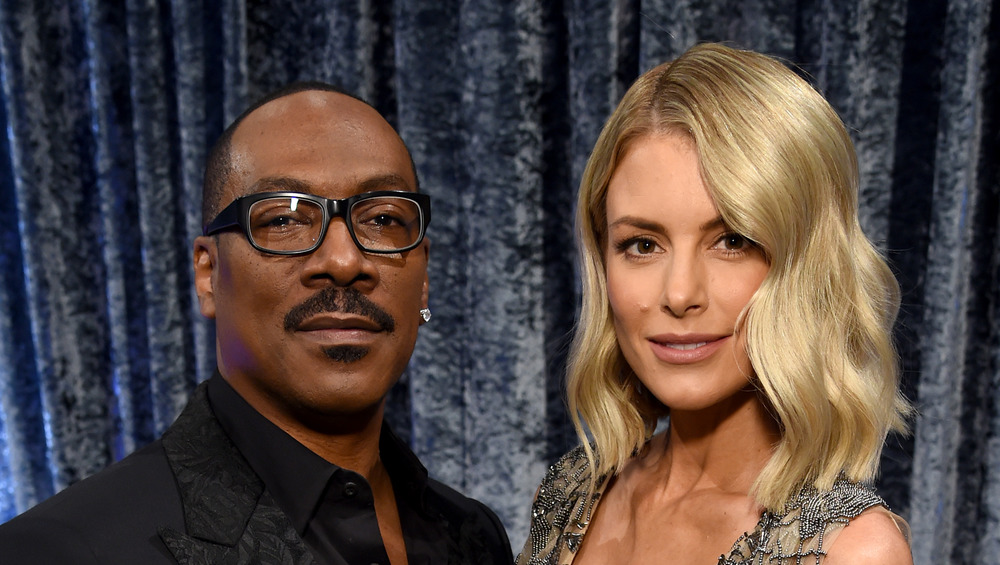 Eddie Murphy in glasses and Paige Butcher smiling, pose together