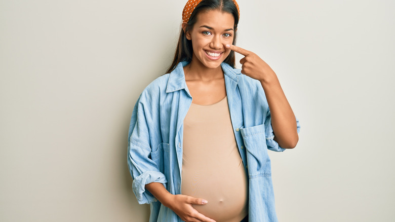 Pregnant woman pointing at her face