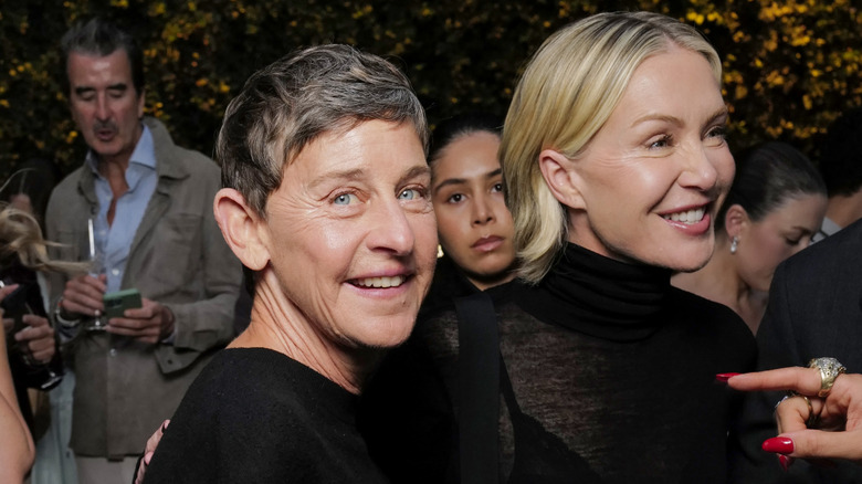 Ellen DeGeneres and Portia De Rossi walking among a crowd
