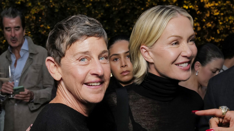 Ellen DeGeneres and Portia de Rossi, both wearing black, standing in front of a group of people