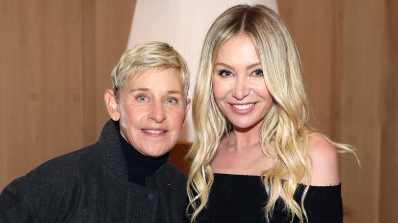 Ellen DeGeneres and Portia de Rossi standing in front of a brown background