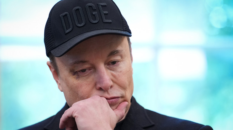 Elon Musk wears a DOGE cap and looks deep in thought