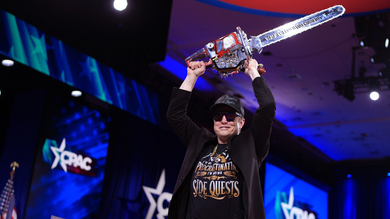 Elon Musk holding chainsaw