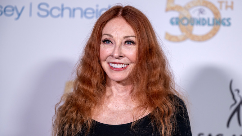 Cassandra Peterson beaming at the cameras on the red carpet for a SAG-AFRA red carpet with natural makeup and her ginger hair in waves