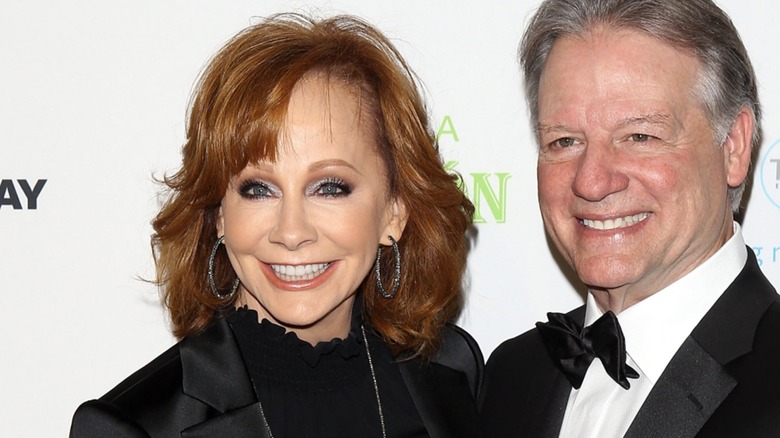 Reba McEntire with guest and sidswept bangs that reveal a very large forehead