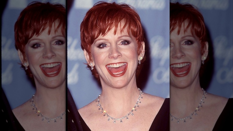 Reba McEntire smiling with mouth open and very short hair