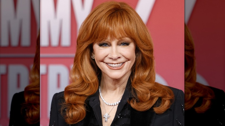Reba McEntire on red carpet, smiling, hair perfectly coiffed and inches below her shoulders