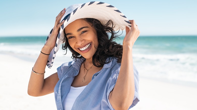 woman wearing straw hat smiling at beach