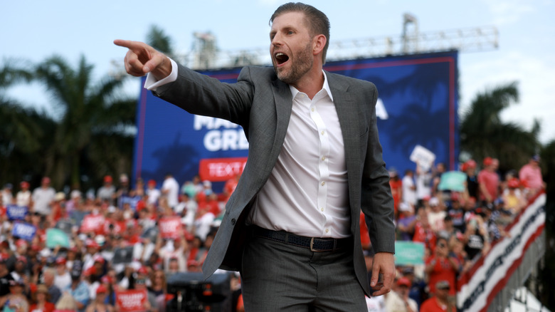 Eric Trump entertaining a crowd in a grey suit with a white shirt