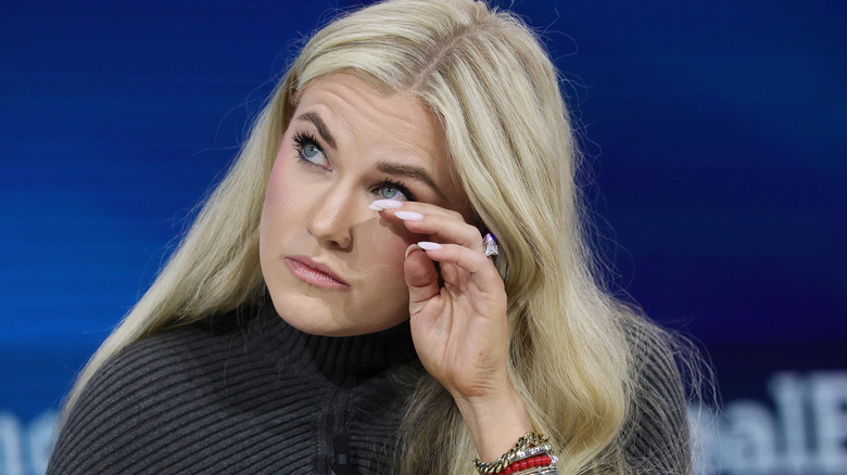Erika Kirk wiping away a tear onstage in a dark grey sweater