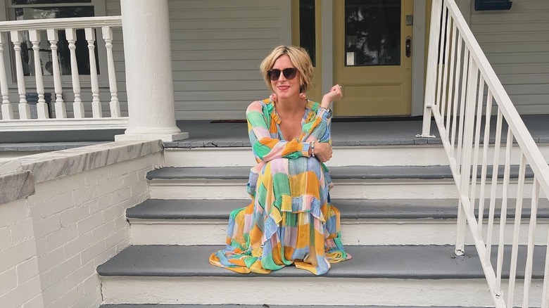 Erin Napier smiling while sitting on front steps of a house.