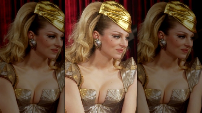 Hunter Schafter smirking in a gold vintage Gaultier corset with a golden hat on teased hair