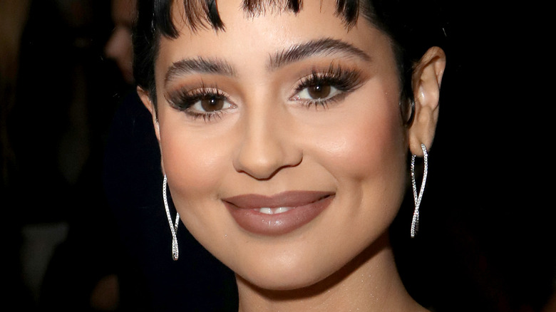 Alexa Demie smiling with bangs and diamond earrings 