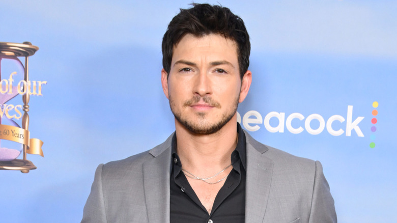 Robert Scott Wilson posing with a neutral expression in a grey suit with a black shirt