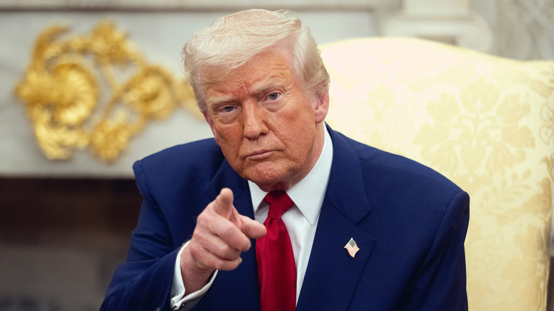 Donald Trump pointing in a navy suit with a red tie