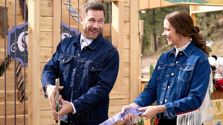 Luke Macfarlane and Amy Acker smiling and cutting a ribbon