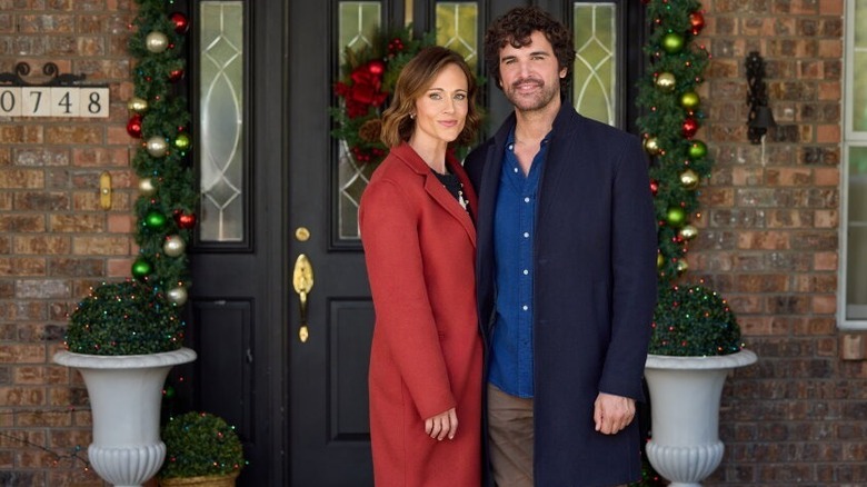 Nikki DeLoach and Juan Pablo Di Pace smiling outside of a house