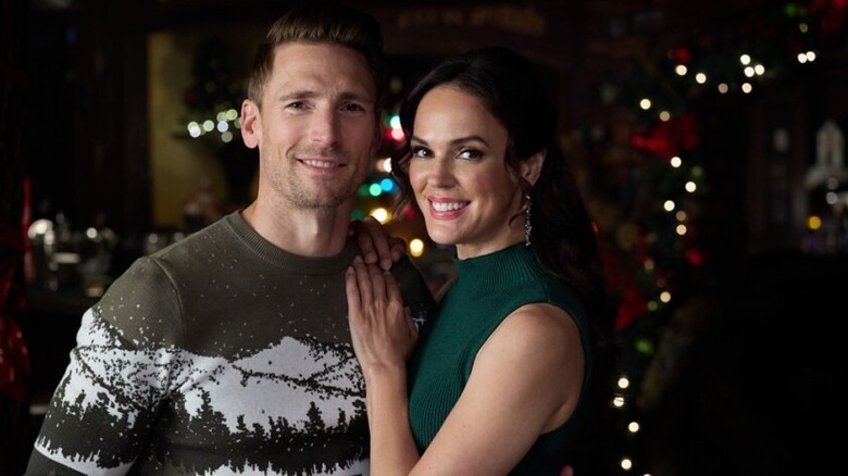 Andrew Walker and Erin Cahill smiling surrounded by Christmas decorations