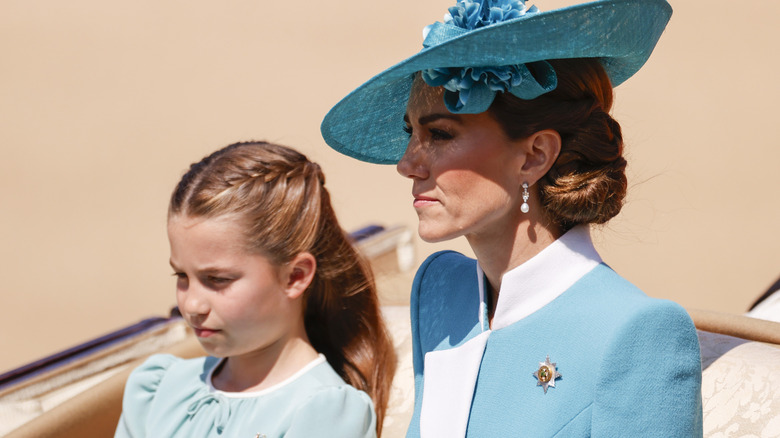 Princess Charlotte sitting beside Kate Middleton in matching light blue outfits