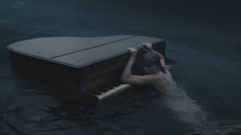 Taylor Swift holding on to a piano while drowning