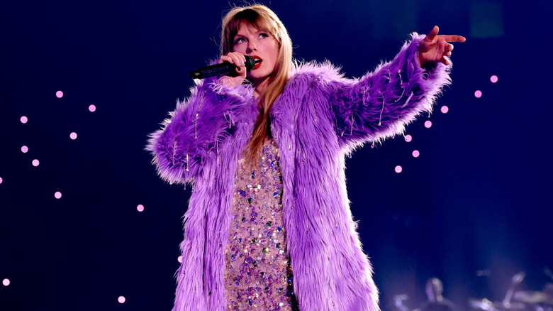Taylor Swift singing on stage in purple coat