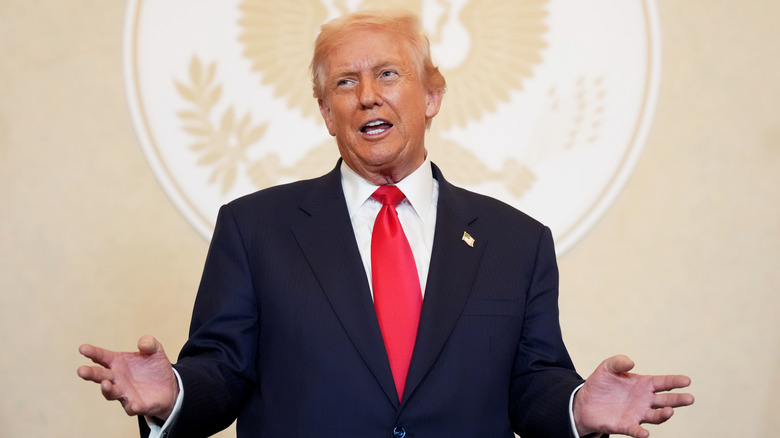 Donald Trump giving a speech in a navy suit with a red tie