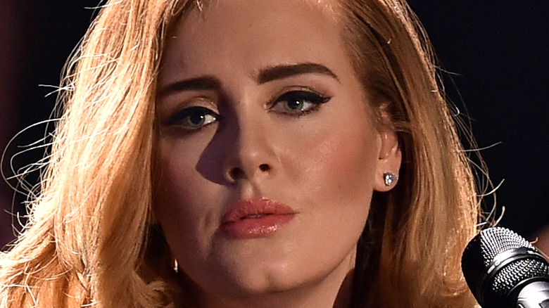 Adele looks sad and thoughtful at a microphone