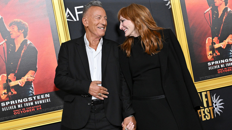 Bruce Springsteen and Patti Scialfa sharing a laugh while holding hands on the red carpet