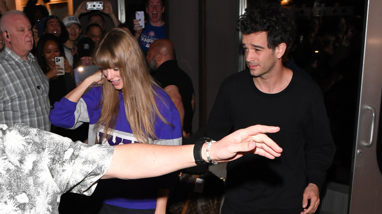 Taylor Swift and Matty Healy surrounded by fans as they leave building in New York