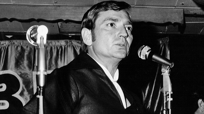 A black-and-white photo of Willie Nelson in front of a microphone