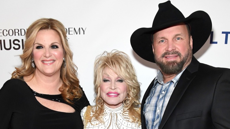 Trisha Yearwood, Dolly Parton, Garth Brooks posing 