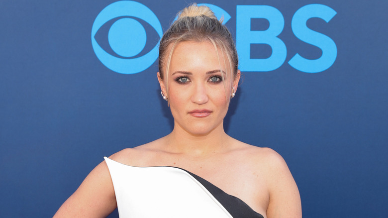 Emily Osment in front of blue backdrop with CBS logo