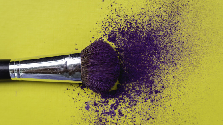 Makeup brush with spilled purple eyeshadow 
