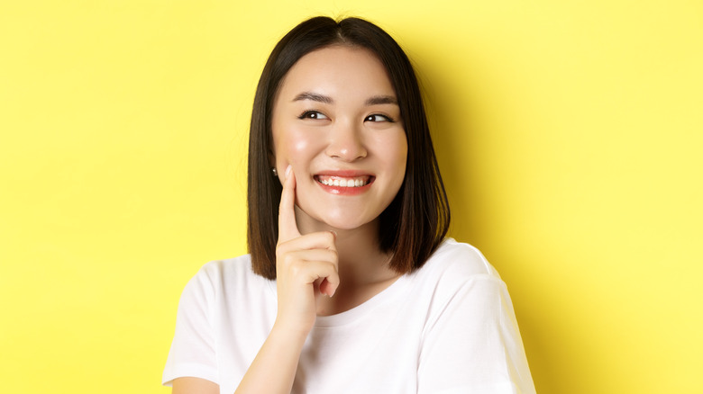 Young woman smiling, touching her cheek