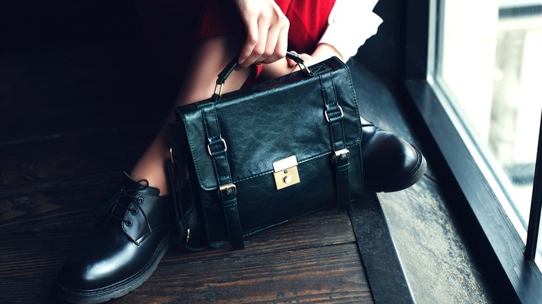 Woman holds briefcases while sitting