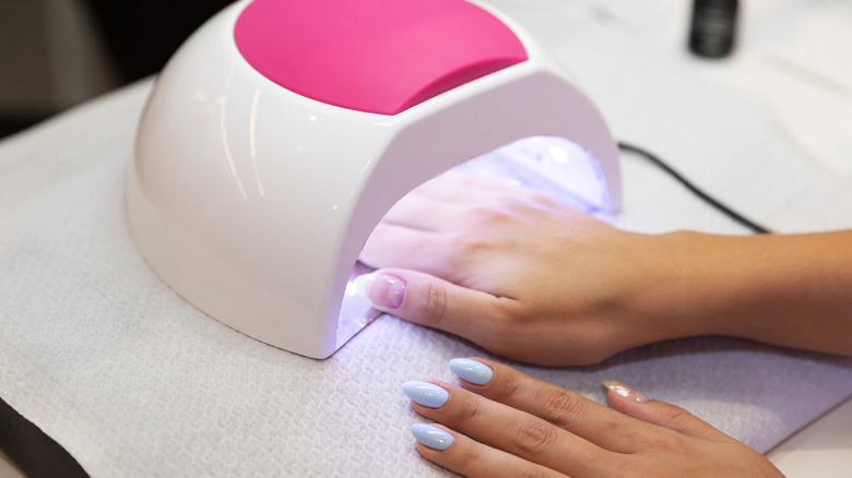 Woman gets gel nails done under UV lamp