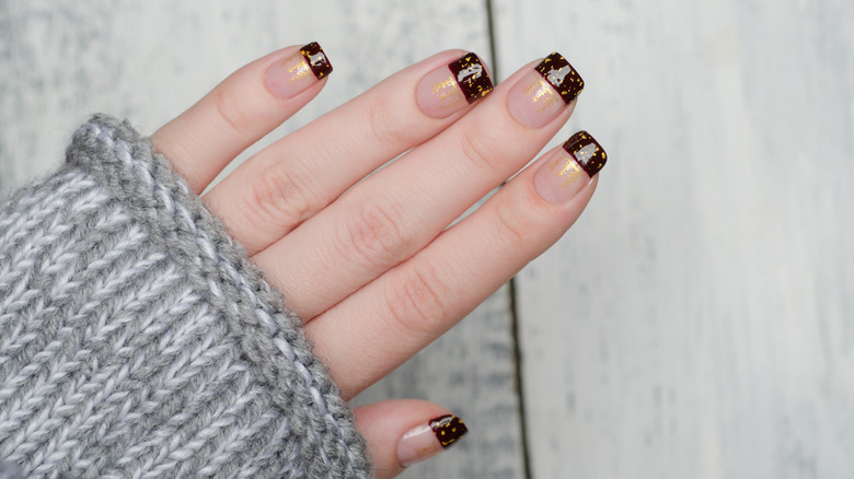 burgundy manicure with gold flakes and negative space