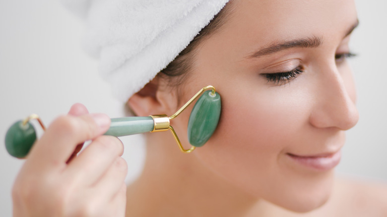 Woman using a jade roller on her face