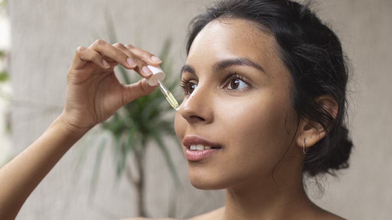 Woman using tea tree oil serum