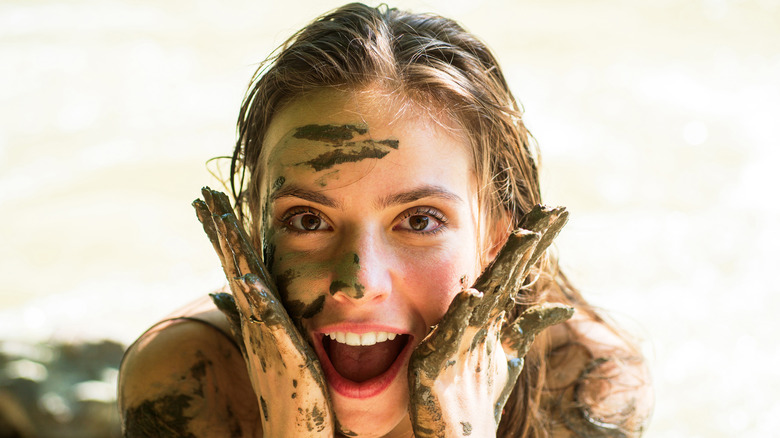Young woman with mud on her face