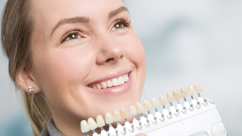 Woman holding teeth coloring swatches 