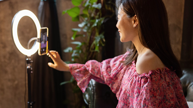 woman sitting in front of a ring lamp taking a selfie