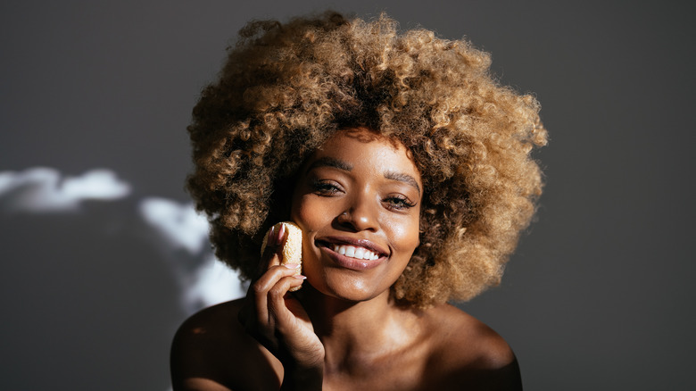 smiling woman wiping a pad on face