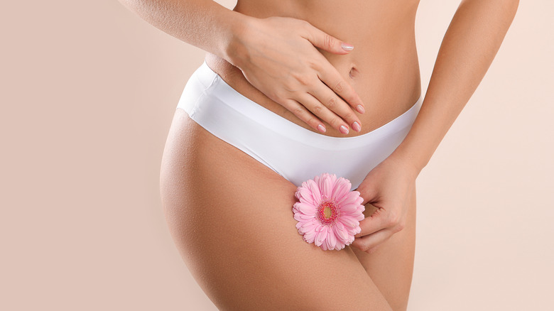 woman holding flower near crotch