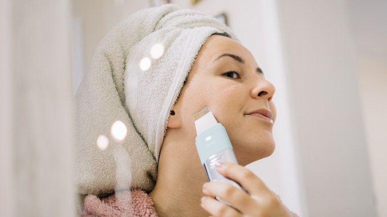 A woman using a skincare spatula on her face 